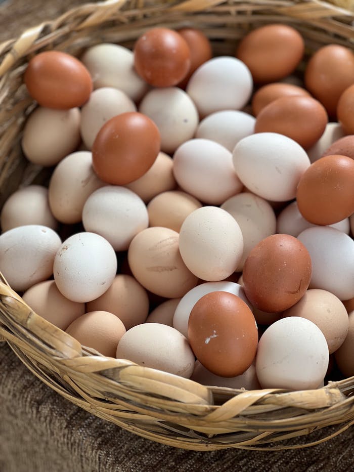 Close-up of a wicker basket full of assorted fresh eggs arranged neatly, emphasizing natural colors.